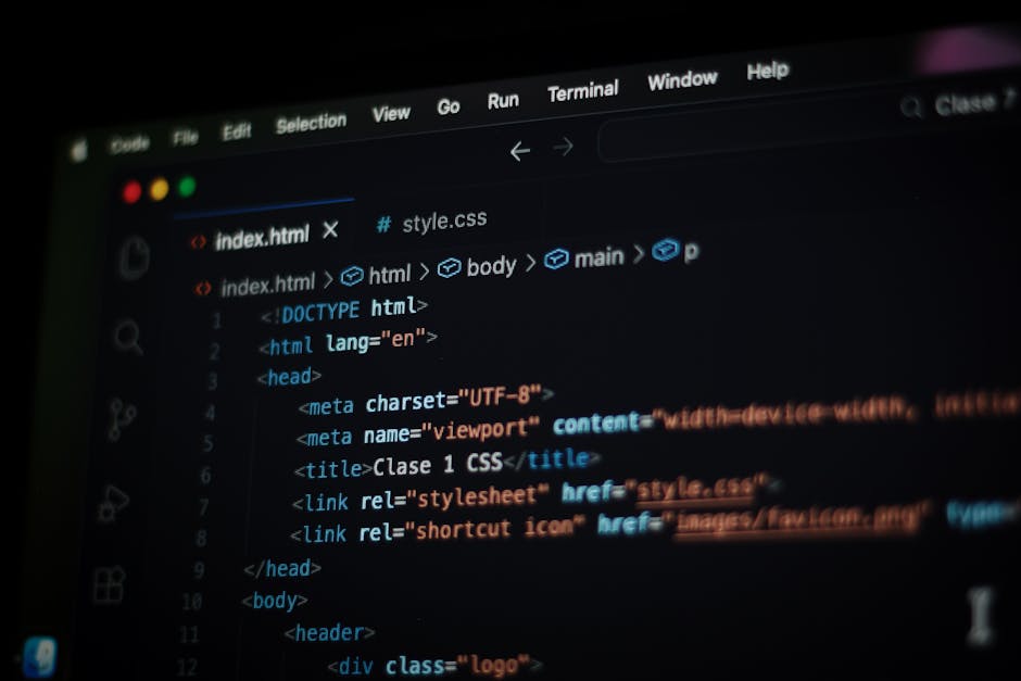 Close-up of a black laptop with a red backlit keyboard displaying lines of colourful code on its screen, placed on a dark surface. Next to the laptop, a white Puma-branded baseball cap with a black lo